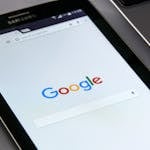 Zbliżenie na tablet z ekranem wyszukiwarki Google, symbolizujące nowoczesne technologie, przeglądanie internetu i skuteczne oferty SEO.