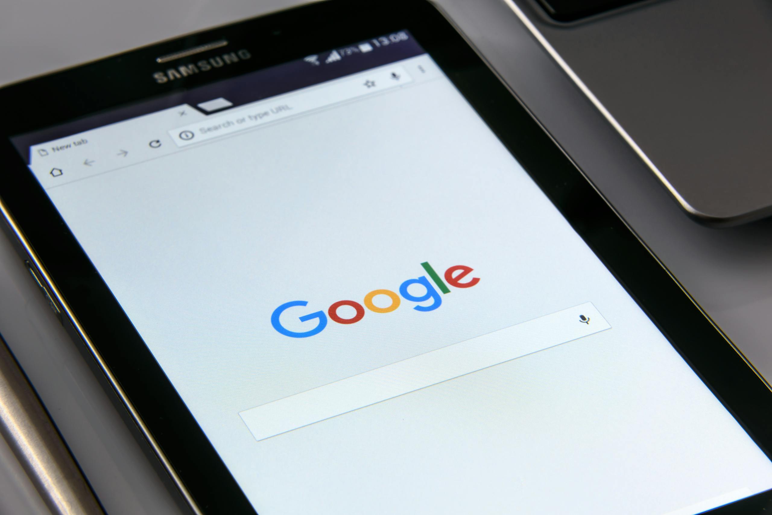 Zbliżenie na tablet z ekranem wyszukiwarki Google, symbolizujące nowoczesne technologie, przeglądanie internetu i skuteczne oferty SEO.